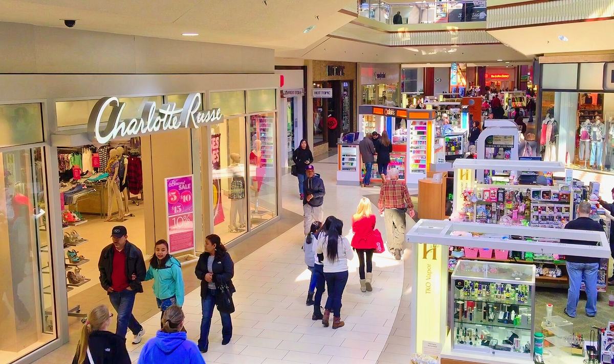 Shoppers walking through a US shopping mall past clothing stores