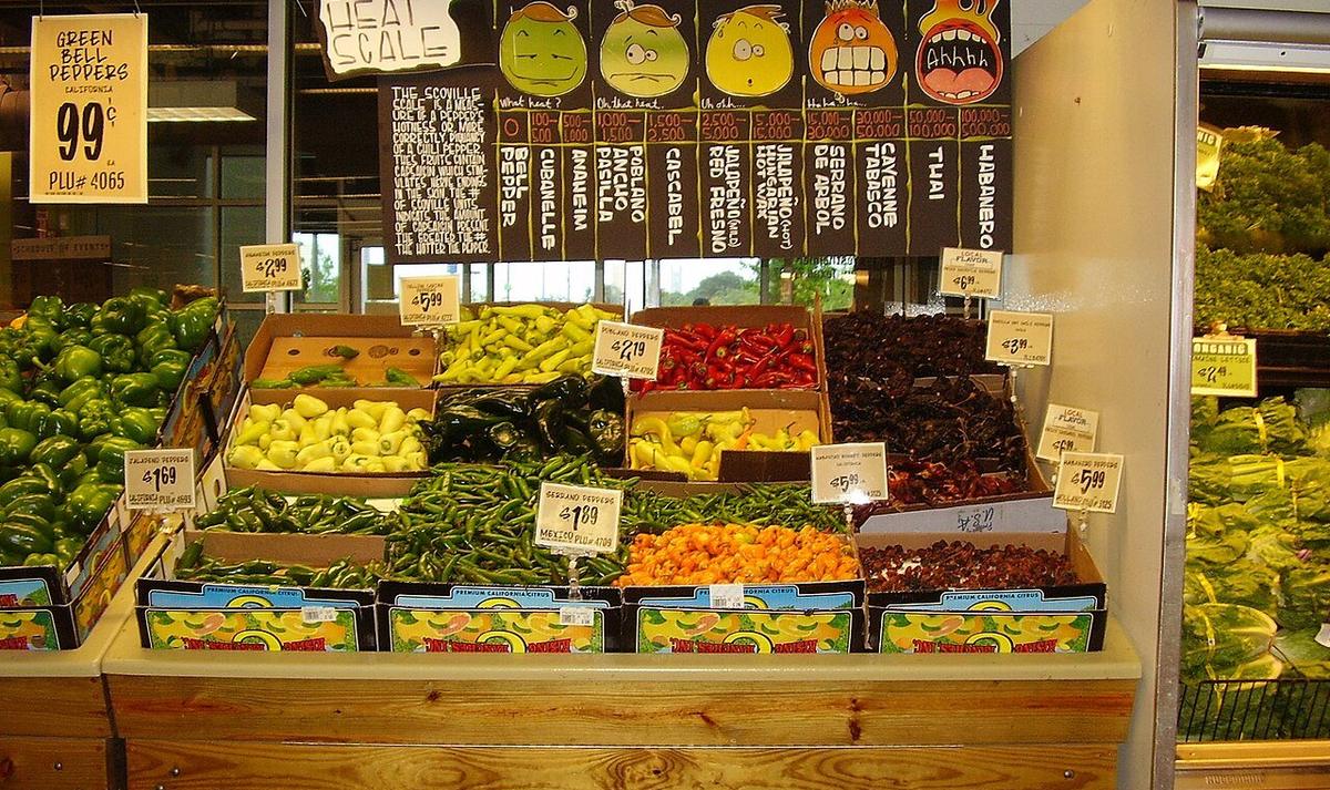 A grocery store display of fresh peppers including jalapenos