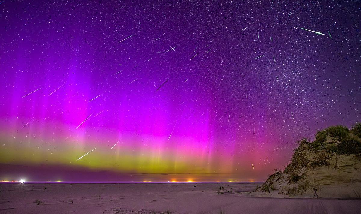A composite night-sky photograph showing many Perseid meteors above an aurora