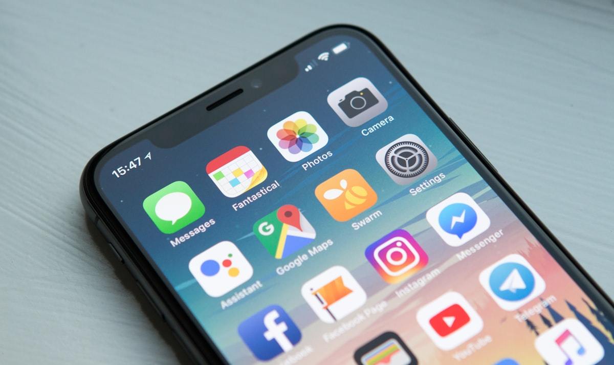 A smartphone home screen showing app icons, resting on a table