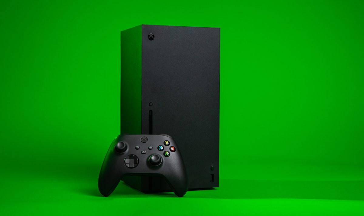 An Xbox Series X console and controller against a green background